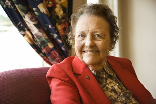 Elderly Caucasian woman by window at retirement community center.