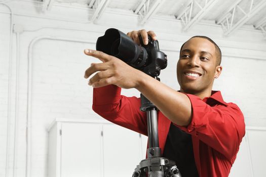 African American young male adult with camera and pointing.