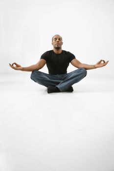 African American young male adult sitting meditating.