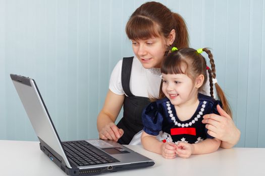 Mother and daughter sitting at table with a laptop