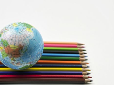 Colored Pencils and Globe on the plain background