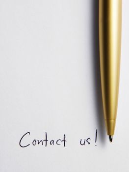 gold color pen on the paper with text contact us