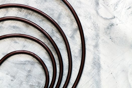 Spiral made from dark wire lying on light gray metal background with copy space