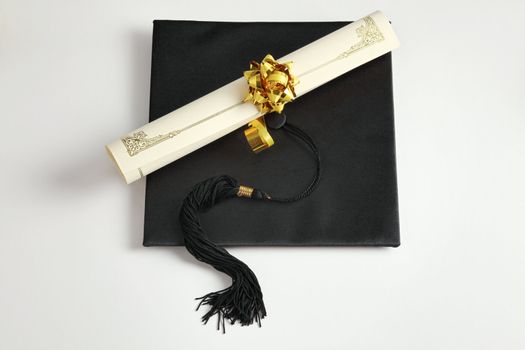 Graduation cap and diploma on the plain background

