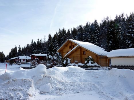 Chalets in Jura mountain Switzerland with lot of snow and fir trees forest behind