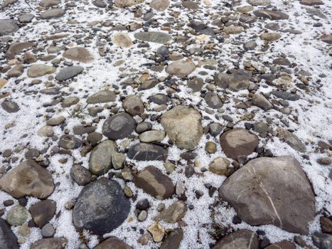 Close up of grey stones and pebbles with snow