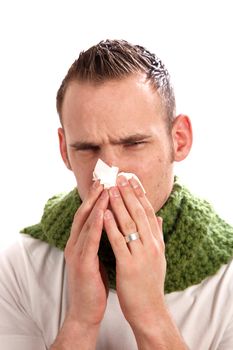 A sick man blows his nose. He wears a scarf.