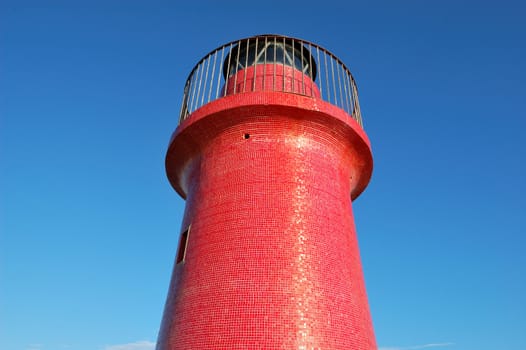 red lighthouse against a summer deep blue sky