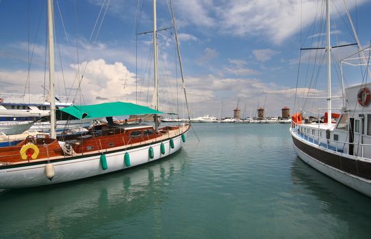 Yachts and the three old mills of the old harbor of Rhodes, Greece