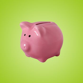 Pink piggybank made of ceramic isolated on green with clipping path