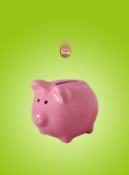 Pink piggybank made of ceramic isolated on green with clipping path