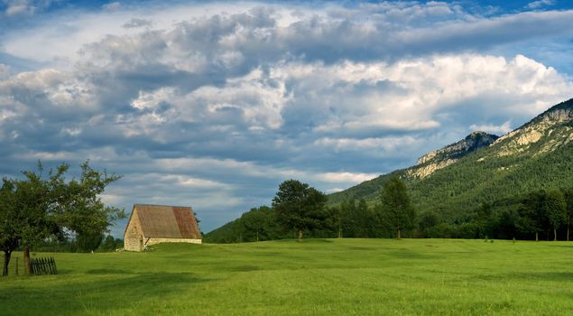 old house on the field with heavy clouds before rain