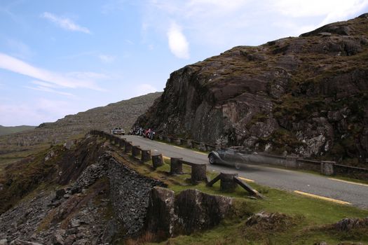 an evening view of winding roads through the mountains of kerry with vintage cars and motorbikes on the roads