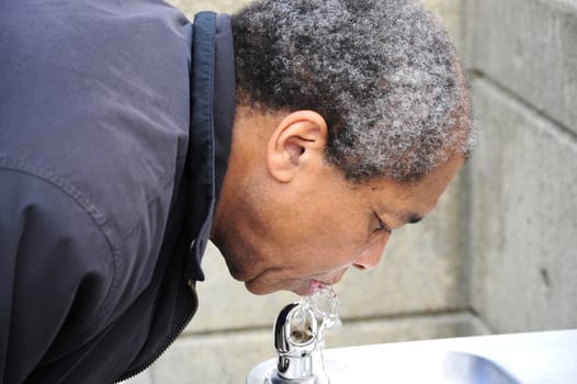 African american man drinking from a water fountain.