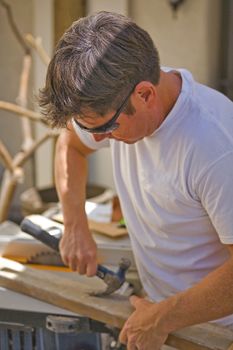 Man using a Hammer to pull a nail out of wood