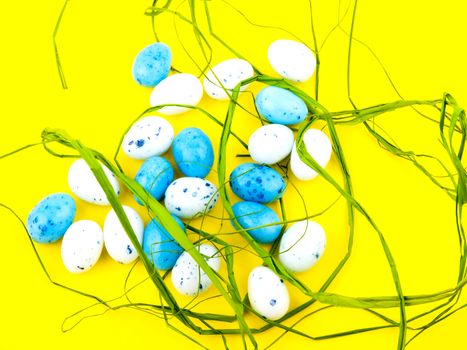 White and blue easter eggs on yellow background.