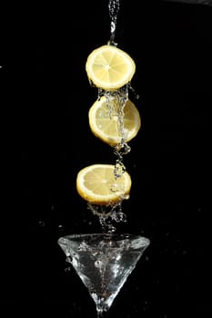 The segments of fruit falling in a glass with a drink