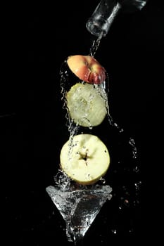 The segments of fruit falling in a glass with a drink
