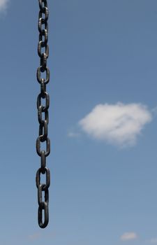 an opened broken chain over a blue clouded sky