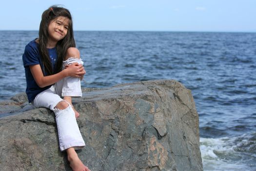 Little girl sitting on rock by lakeshore