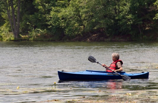 An active female senior citizen paddling around in a kayak.