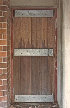 Old Looking Steel Reinforced Door with Wood Boards and Red Brick Wall with mortar.