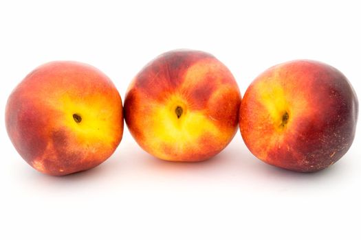Three ripe nectarines on a white background