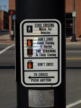 A street crossing sign on a pole at a busy interesction