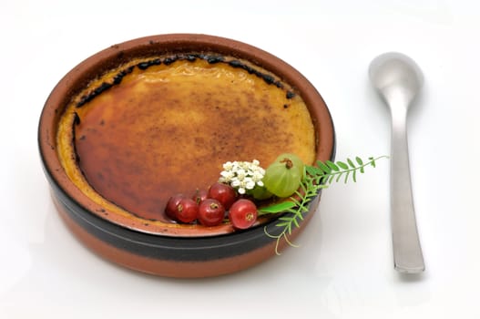 French creme brulee served in an earthenware dish and decorated with small fruits