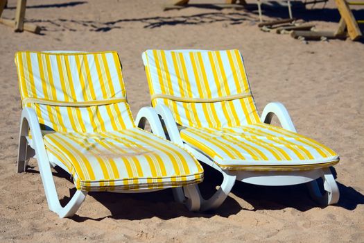 Egypt, two deck chairs with mattresses are on the beach.