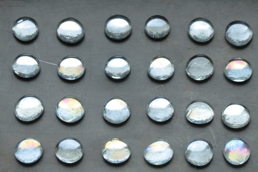 Great number of glass balls lyig in a row on rusty metal background