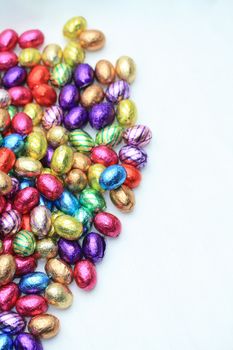 A pile of colored easter chocolate eggs with copy space