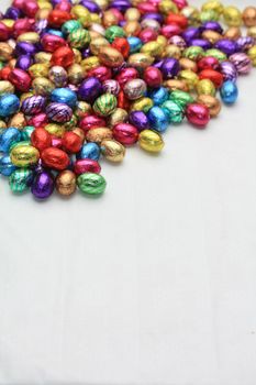 A pile of colored easter chocolate eggs with copy space