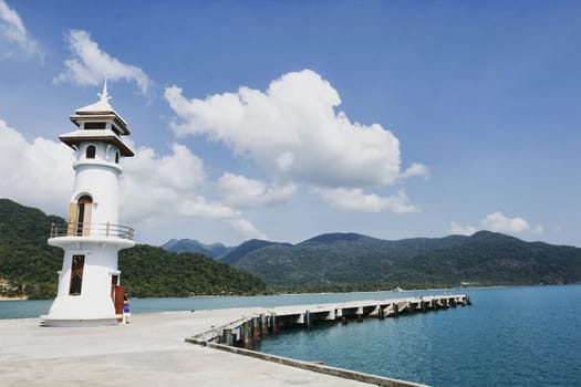 Old abandoned lighthouse set against tropical island background with blue sky and mountains