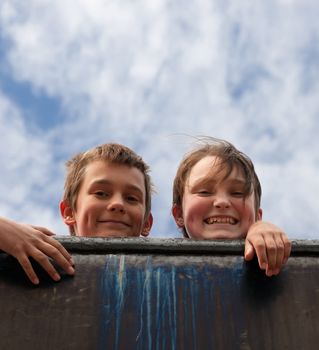 two kids looking over old metal wall