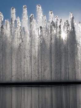 The sun through a fountain and reflecting pool.
