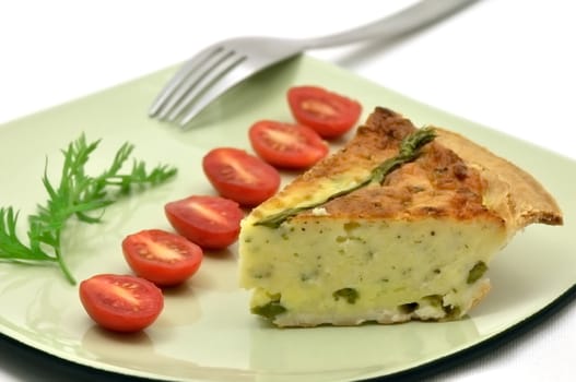 Asparagus quiche slice on a green plate with tomatoes