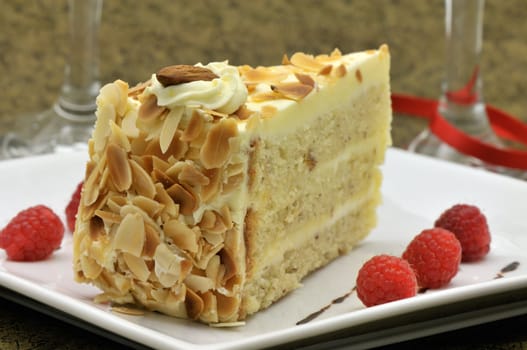 Almond and cream cake slice on a plate with raspberries