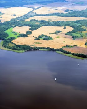 Aerial view of the lake and agricultural land in the summer time. Small waves on the water surface.