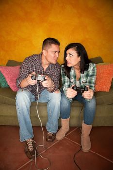 Attractive Hispanic Couple Playing a Video Game with Handheld Controllers