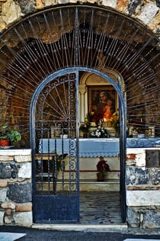 Gate opening in front of an old Italian chapel