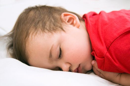 Boy in red dress sleeping on bed in white background