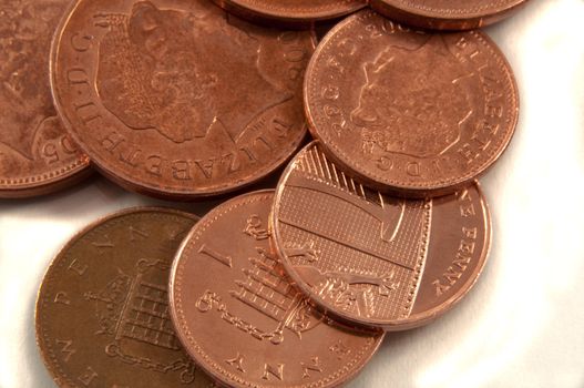 Close and low level capturing a selection of British coins arranged over white.