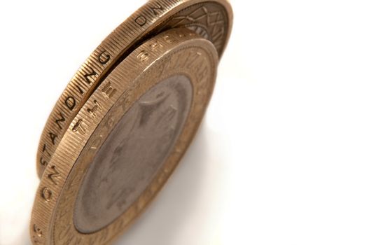 Close up capturing a selection of British two pound coins arranged over white.