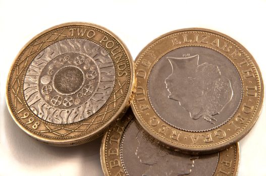 Close up capturing a selection of British two pound coins arranged over white.
