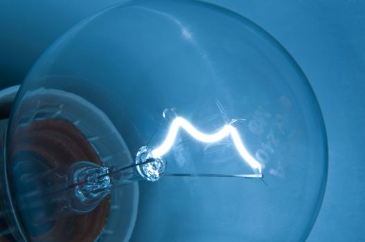 Close up, low level capturing an illuminated light filament with blue background.