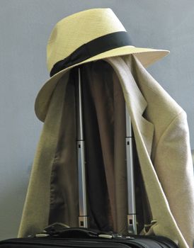 A hat, coat and carry on luggage waiting at the airport.
