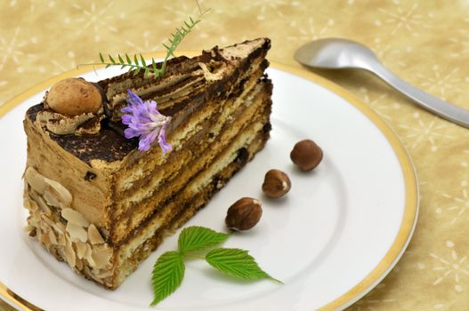 Hazelnut and chocolate cake slice decorated with leaves and purple flower