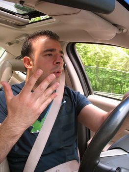 A young man that is driving seems to be experiencing some minor road rage.