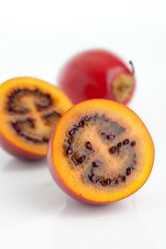 Juicy tamarillo on white background, one whole and one cut in two